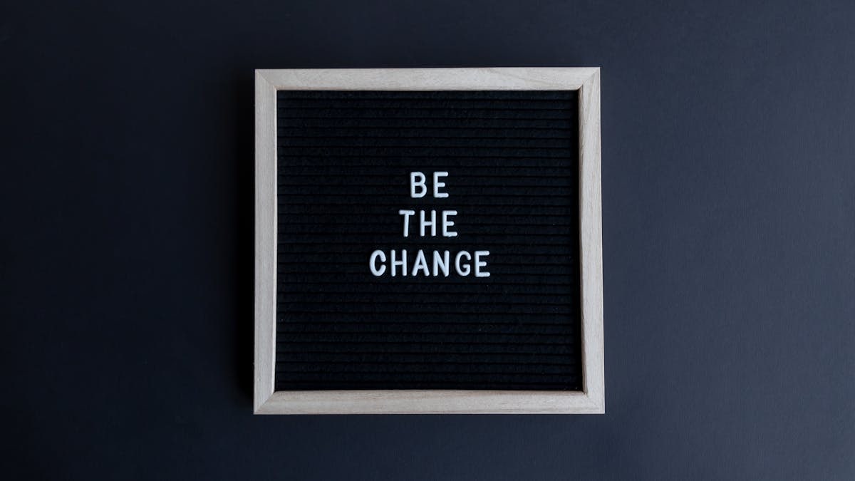A simple letter board with the motivational message 'Be the Change' on a dark background.